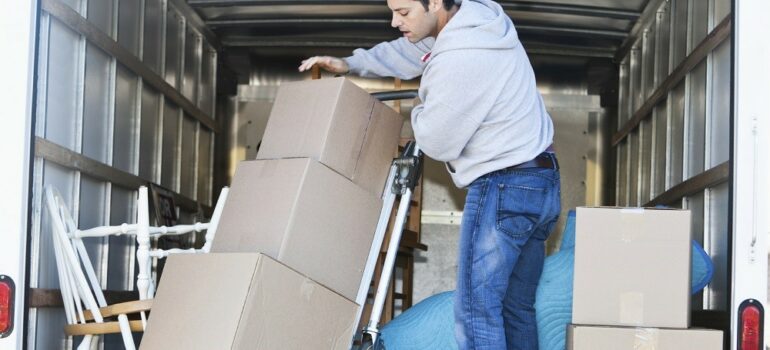 Mid adult man (30s) standing in moving truck, moving boxes.