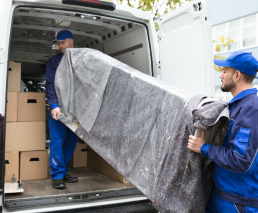 Two Delivery Men Unloading Furniture From Vehicle Two Young Delivery Men In Uniform Unloading Furniture From Vehicle